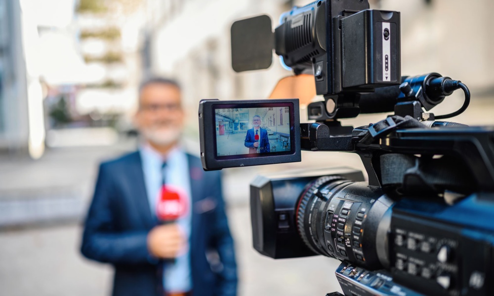 Journalist being recoded while doing a news alert on location in a city.